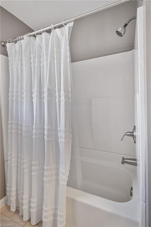 bathroom with shower / tub combo with curtain and tile patterned floors