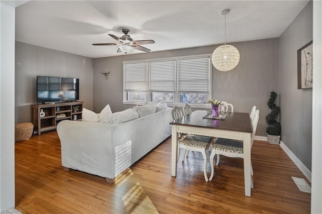 living room with ceiling fan with notable chandelier and light hardwood / wood-style floors