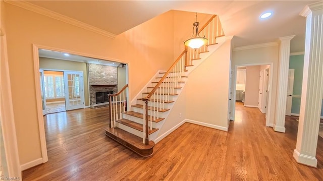 1005 Fallbrook Ln, Lewisville, NC 27023 - staircase with crown molding, wood finished floors, baseboards, a brick fireplace, and decorative columns
