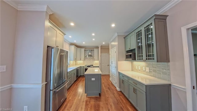 1005 Fallbrook Ln, Lewisville, NC 27023 - kitchen featuring appliances with stainless steel finishes, wall chimney exhaust hood, ornamental molding, wood finished floors, and tasteful backsplash