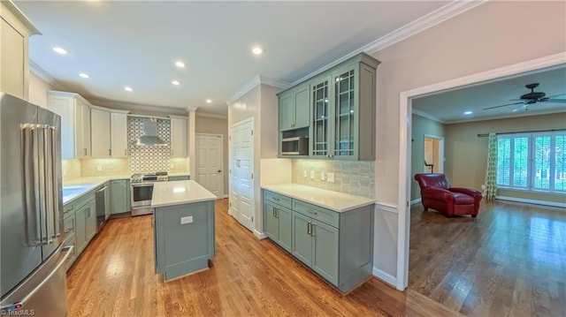 1005 Fallbrook Ln, Lewisville, NC 27023 - kitchen featuring appliances with stainless steel finishes, crown molding, wall chimney range hood, a center island, and light wood finished floors