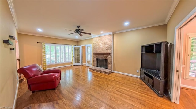 1005 Fallbrook Ln, Lewisville, NC 27023 - living room featuring a ceiling fan, healthy amount of natural light, light wood-style flooring, a fireplace, and crown molding