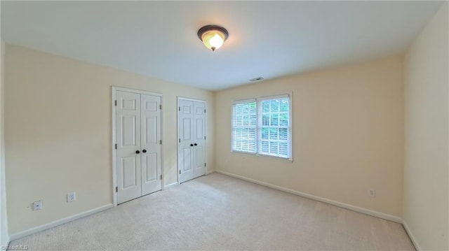 1005 Fallbrook Ln, Lewisville, NC 27023 - unfurnished bedroom with multiple closets, carpet flooring, and baseboards
