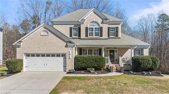 view of front of home featuring brick siding, covered porch, an attached garage, a front yard, and driveway