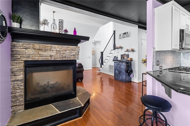 interior space featuring dark wood-type flooring, white cabinetry, appliances with stainless steel finishes, decorative backsplash, and dark countertops