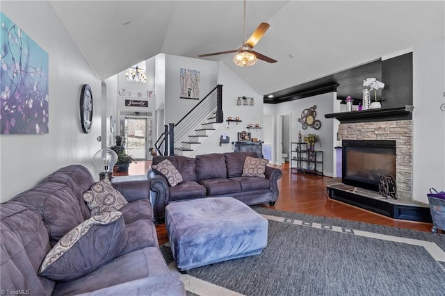 living room featuring high vaulted ceiling, dark wood-style flooring, a fireplace, a ceiling fan, and stairway