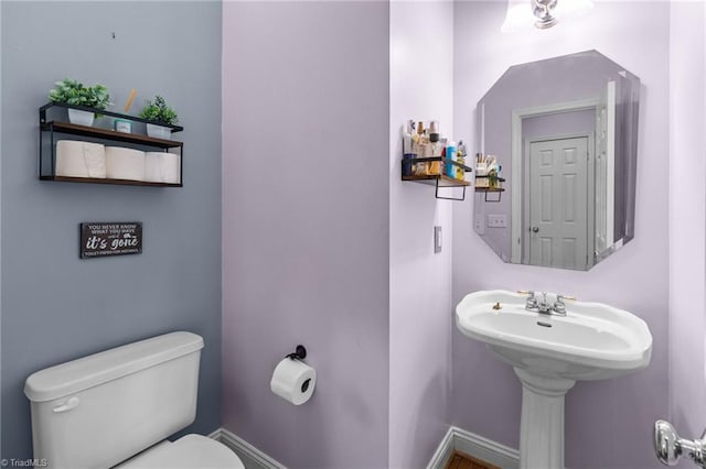 half bath with baseboards and toilet