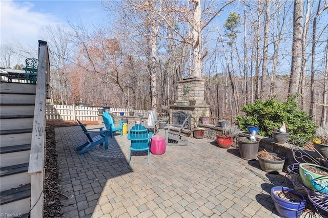 view of patio / terrace with an outdoor stone fireplace and fence