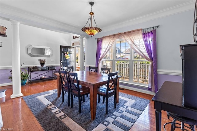 dining space with wood finished floors and ornate columns