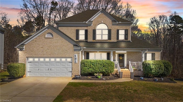 view of front of house featuring a garage, a front lawn, concrete driveway, and brick siding