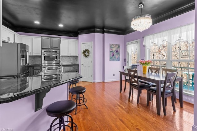 dining room featuring recessed lighting, baseboards, light wood-style floors, ornamental molding, and an inviting chandelier