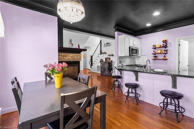 dining room with dark wood-style floors, a chandelier, crown molding, and stairs