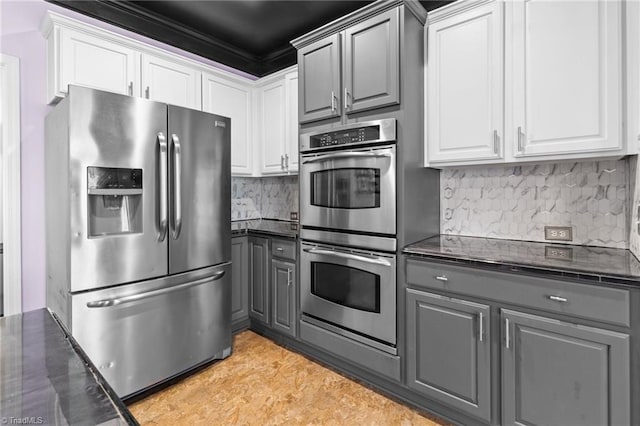 kitchen featuring tasteful backsplash, dark countertops, appliances with stainless steel finishes, gray cabinetry, and white cabinetry