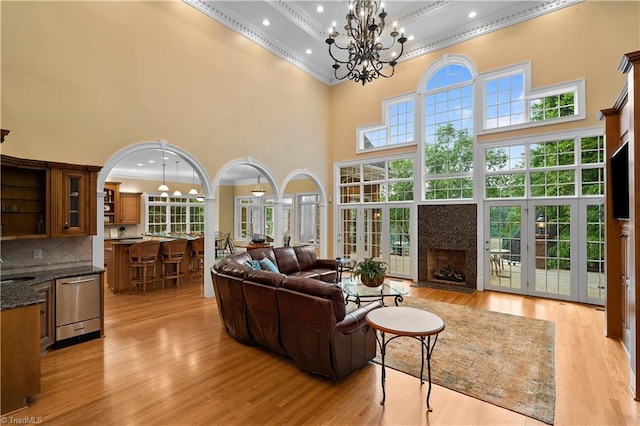 344 Lake Point Ln, Belews Creek, NC 27009 - living room with a towering ceiling, ornamental molding, a chandelier, a fireplace, and light wood-style floors