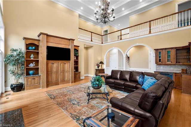 344 Lake Point Ln, Belews Creek, NC 27009 - living area with arched walkways, a towering ceiling, ornamental molding, a chandelier, and light wood-type flooring