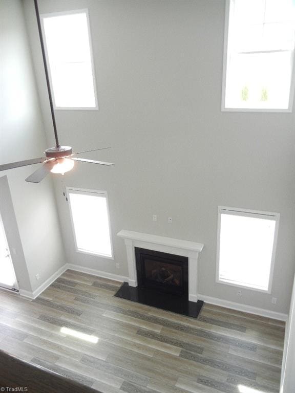 715 Cannonade Dr, Whitsett, NC 27377 - unfurnished living room with ceiling fan, wood finished floors, a fireplace, plenty of natural light, and a high ceiling