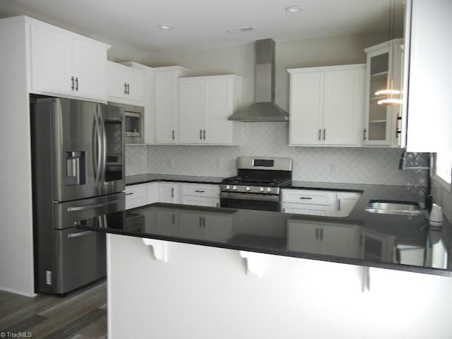 715 Cannonade Dr, Whitsett, NC 27377 - kitchen featuring appliances with stainless steel finishes, wall chimney exhaust hood, a peninsula, dark countertops, and recessed lighting