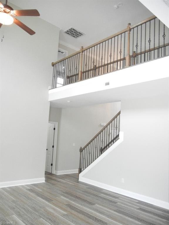 715 Cannonade Dr, Whitsett, NC 27377 - unfurnished living room with a high ceiling, ceiling fan, wood finished floors, and stairway