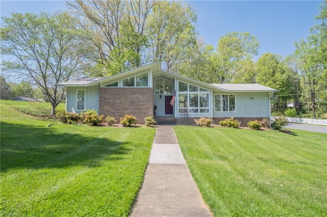 mid-century modern home featuring a front lawn and brick siding