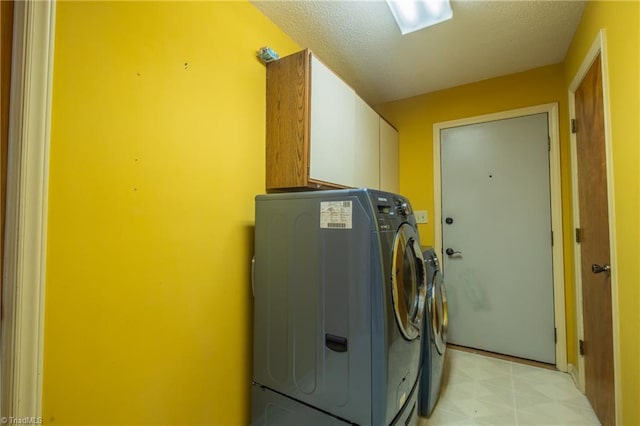 washroom with cabinet space, washer and dryer, and light floors