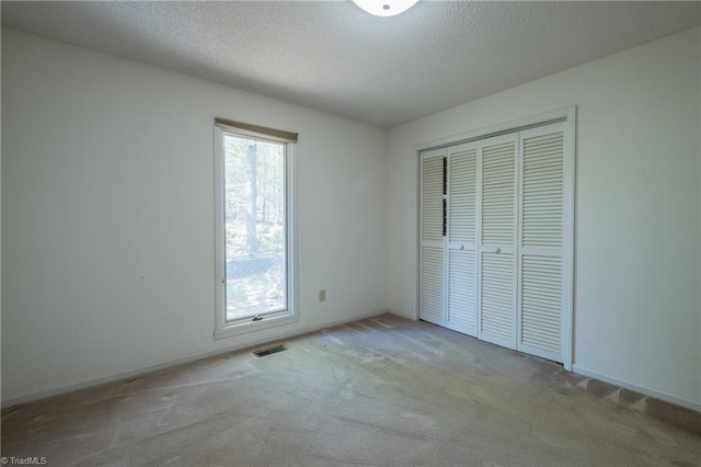 unfurnished bedroom with carpet floors, a textured ceiling, a closet, and baseboards