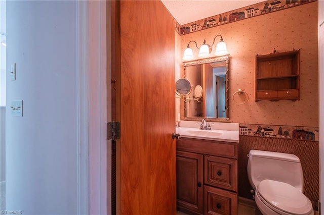 bathroom featuring wallpapered walls, toilet, and vanity
