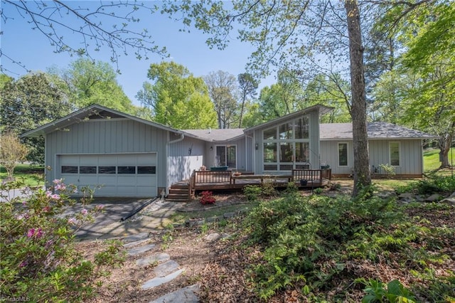 back of house featuring concrete driveway, an attached garage, and a wooden deck