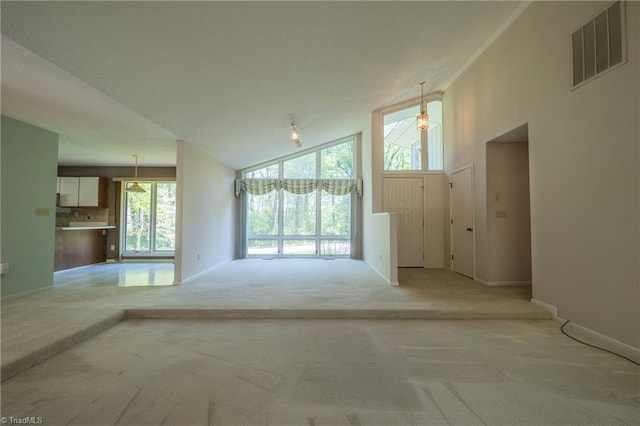 unfurnished living room featuring light colored carpet, high vaulted ceiling, healthy amount of natural light, and baseboards