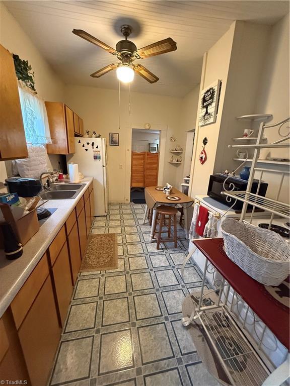 535 Worth St, Mount Airy, NC 27030 - kitchen with brown cabinetry, freestanding refrigerator, ceiling fan, a sink, and light floors
