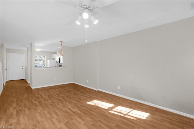 unfurnished room featuring ceiling fan with notable chandelier and wood-type flooring