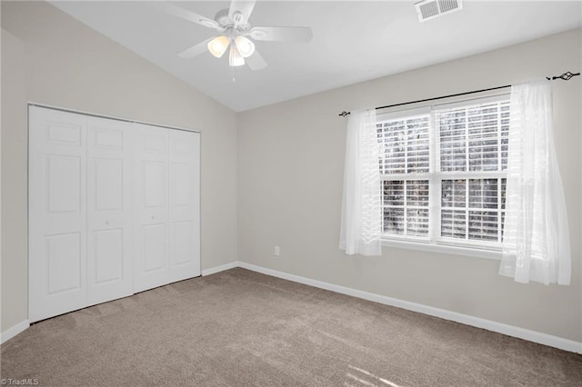 unfurnished bedroom with ceiling fan, a closet, vaulted ceiling, and carpet floors