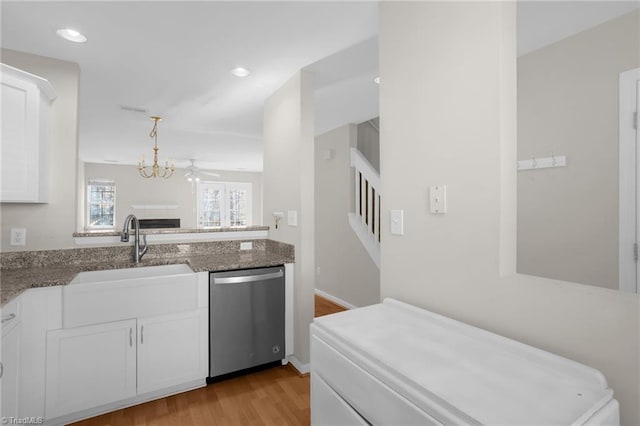 kitchen featuring white cabinetry, light wood-type flooring, dark stone counters, stainless steel dishwasher, and sink