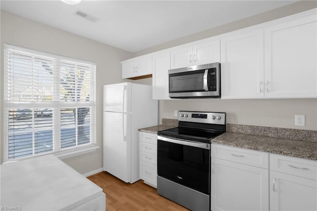 kitchen with white cabinets, light wood-type flooring, and appliances with stainless steel finishes