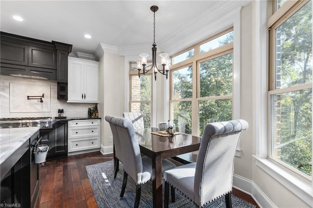 dining space with a wealth of natural light, dark hardwood / wood-style flooring, crown molding, and a notable chandelier