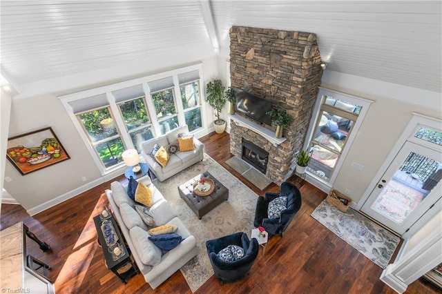 living room with dark hardwood / wood-style flooring, a stone fireplace, and vaulted ceiling