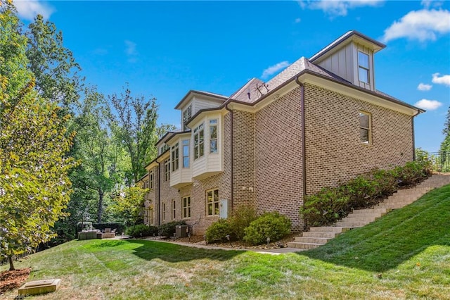 view of side of home featuring central AC and a yard