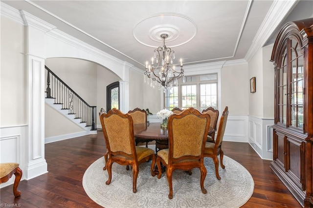 dining area featuring dark hardwood / wood-style flooring, decorative columns, ornamental molding, and a notable chandelier