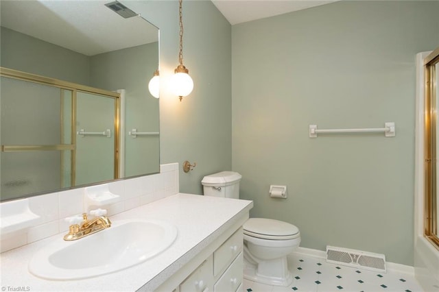 bathroom featuring tasteful backsplash, vanity, toilet, and a shower with shower door