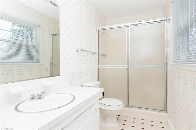 bathroom featuring tile patterned floors, vanity, toilet, and a shower with shower door