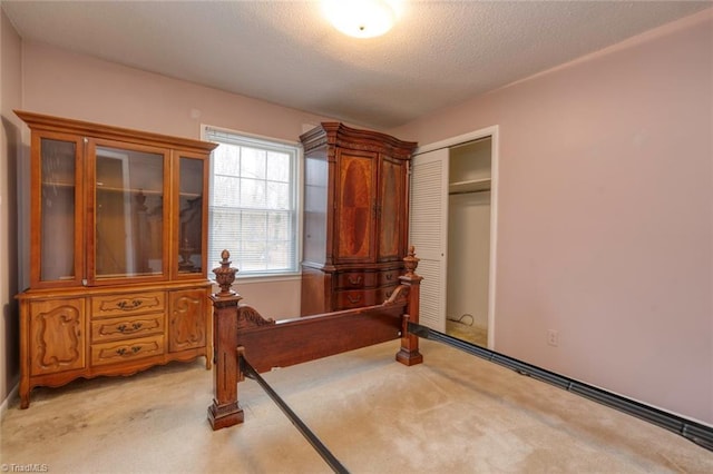 bedroom featuring light colored carpet, a textured ceiling, and a closet