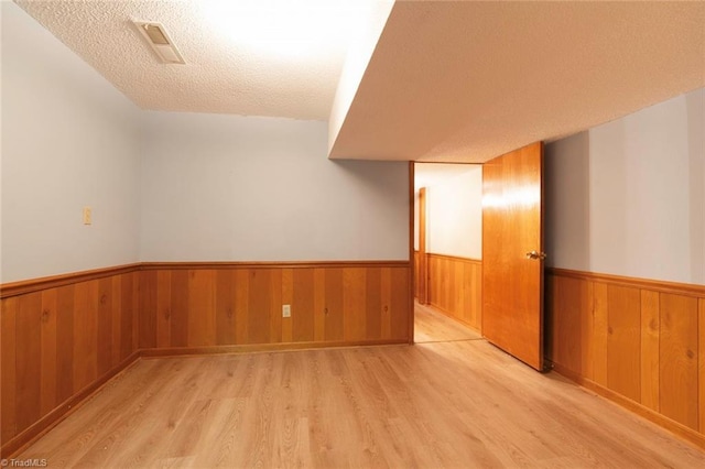 spare room featuring light hardwood / wood-style flooring and a textured ceiling