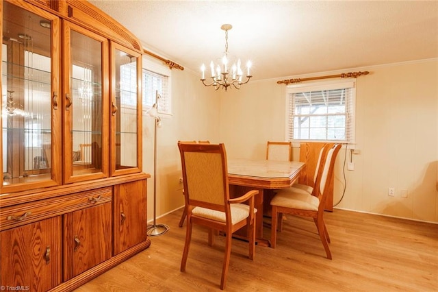 dining space with ornamental molding, an inviting chandelier, and light wood-type flooring