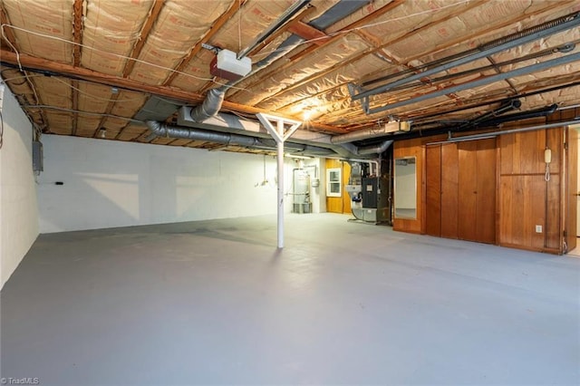 basement featuring heating unit, wooden walls, and water heater