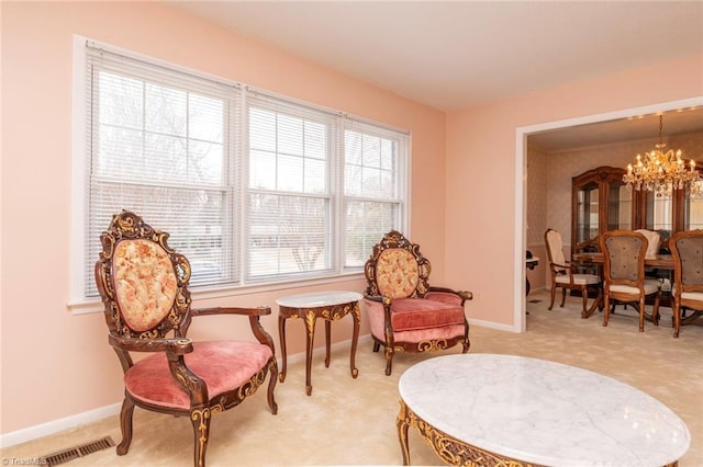 living area with an inviting chandelier and light carpet