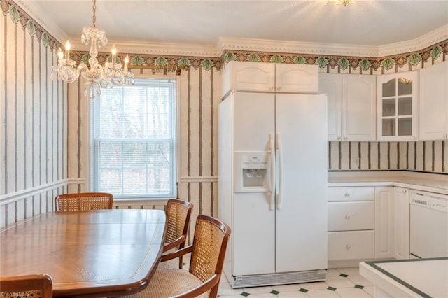 kitchen with decorative light fixtures, white cabinetry, a chandelier, crown molding, and white appliances