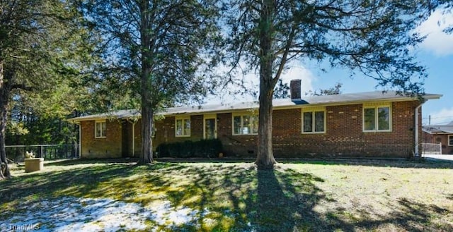 view of front facade with brick siding, fence, a chimney, and a front lawn