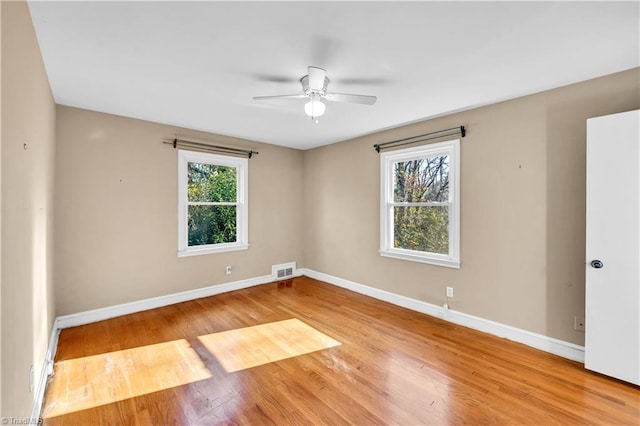 spare room featuring ceiling fan, light wood-type flooring, and a wealth of natural light