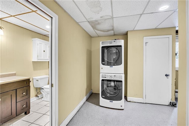 laundry room featuring light tile patterned floors, stacked washer and dryer, and wooden walls