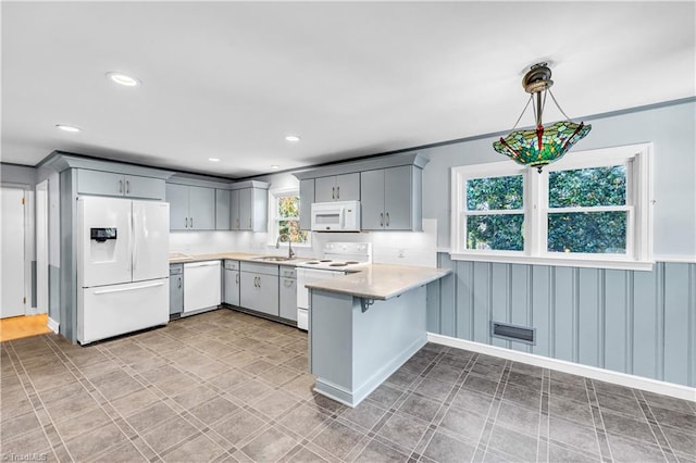 kitchen featuring gray cabinets, kitchen peninsula, decorative light fixtures, and white appliances