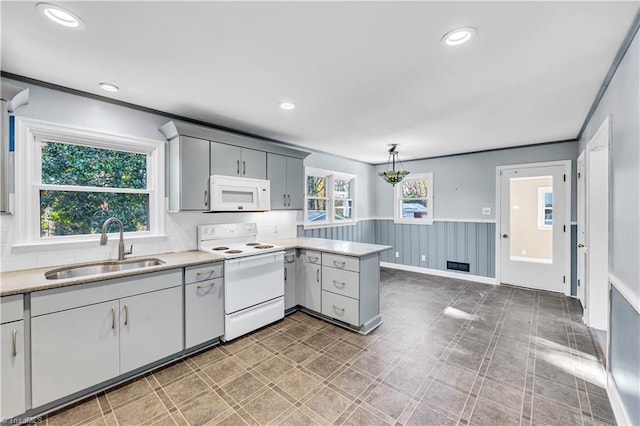 kitchen featuring kitchen peninsula, white appliances, sink, gray cabinets, and hanging light fixtures